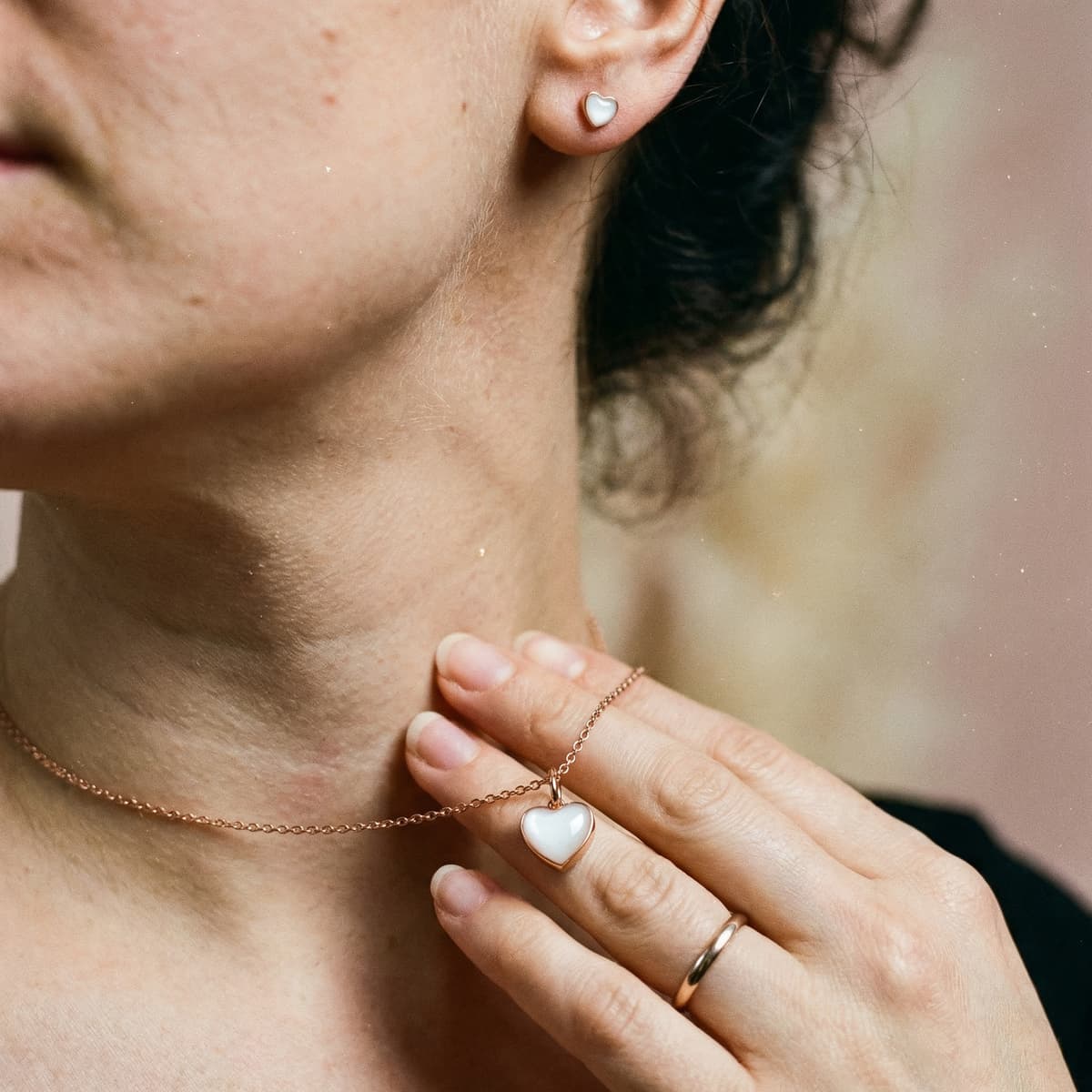 Frau trägt eine herzförmige Milchschmuck-Halskette in Roségold mit passendem Ohrring – ein liebevolles Geschenk zur Stillreise als persönliches Erinnerungsstück.