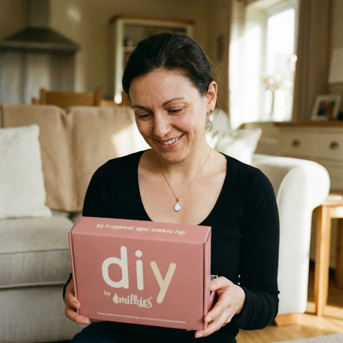Lächelnde Mutter hält das DIY by MILKIES Kit in den Händen – eine gute Wahl, um zuhause mit professioneller Technologie eine persönliche kette muttermilch als Erinnerungsstück selbst zu gestalten.